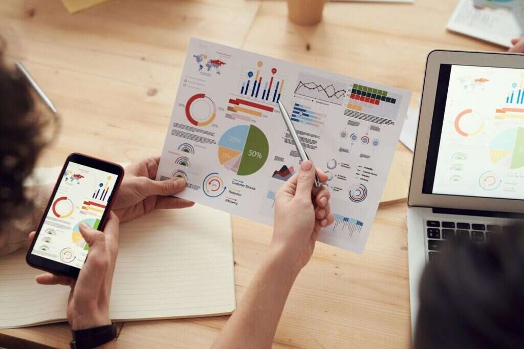 Equipo analizando gráficos en una reunión de negocio con portátiles y móviles