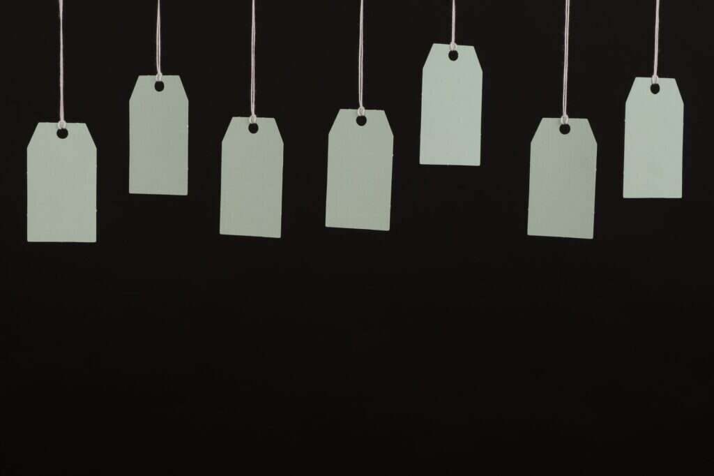 Varias etiquetas de precio en blanco colgando de hilos sobre fondo negro
